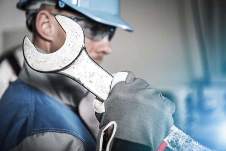 A worker carries a large wrench.